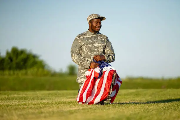 Photo of Soldier at cemetery holding folded American flag paying tribute to his fallen comrades.