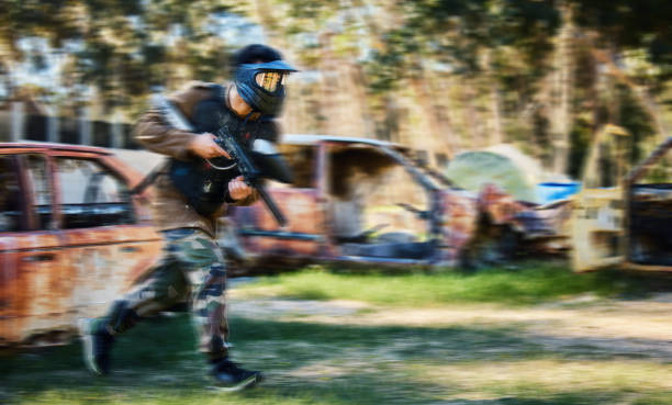 man, paintball and rush for intense battle or war in the forest running to attack on grass field. male paintballer or soldier moving fast to push enemy defense in extreme adrenaline sports outdoors - paintballing violence exercising sport imagens e fotografias de stock