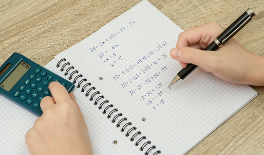 Solve a task, a mathematical equation in a notebook, closeup