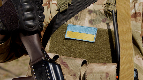 Soldado ucraniano en uniforme militar con una bandera y un chevron que representa la bandera de Ucrania y el símbolo nacional photo
