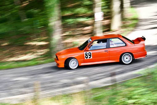 Mythical 1988 BMW E30 driving at full speed on a country road in  Belgium  with a motion blur.