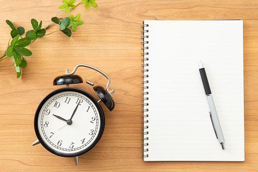 A notebook and an alarm clock on the desk.