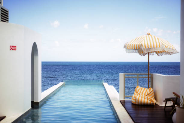 istock Clear Blue Sky Beach Villa with Infinity Pool and Wooden Patio Deck 1620347436