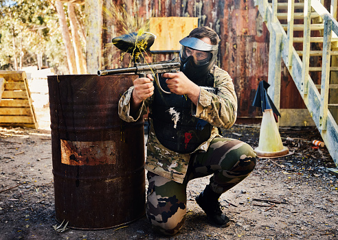 Paintball, target training or male with gun in shooting game playing with on fun battlefield mission. Aim or focused man with army weapons gear for survival in outdoor challenge competition