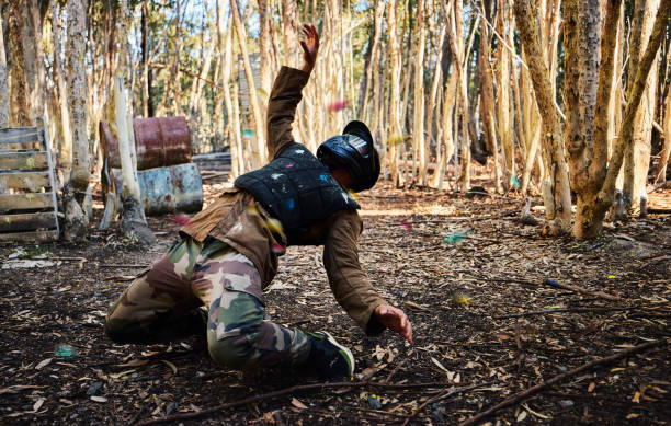 Man, paintball and dodging shots in the matrix for intense battle or war in the forest on knees. Male paintballer or soldier ducking to dodge paint balls in extreme adrenaline sports outdoors hombre, paintball y esquivar disparos en la matriz para una batalla intensa o una guerra en el bosque de rodillas. paintballer masculino o soldado agachándose para esquivar bolas de pintura en deportes extremos de adrenalina al aire libre