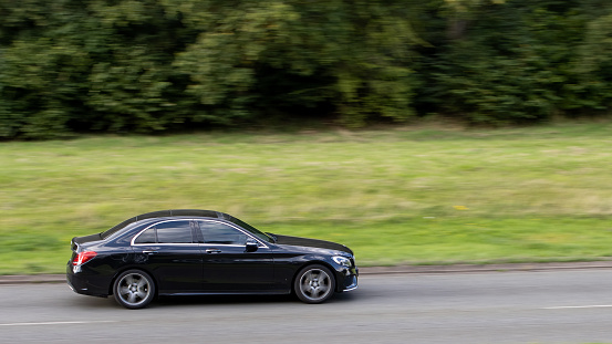 Milton Keynes, UK - Aug 16th 2023:  2014 black Mercedes Benz C 200 car travelling on an English country road.
