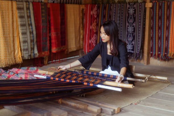 Young Indonesian Woman Learning To Handweave Traditional Woven Tenun Cloth stock photo
