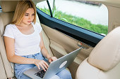 of a beautiful and confident woman working on a laptop while sitting in the car. Business concept.