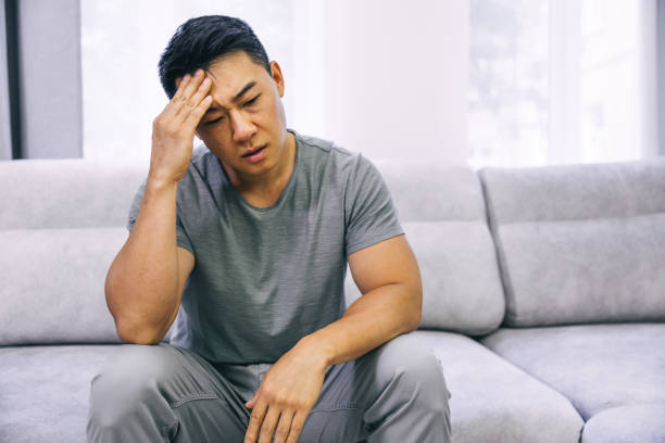 istock Feeling stressed. Frustrated handsome young man touching his head and keeping eyes closed while sitting on the couch at home 1620397795