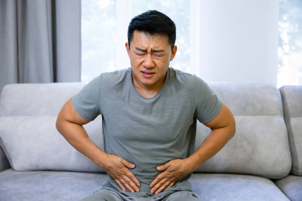 istock Young asian man suffering from abdominal pain at home 1620397811