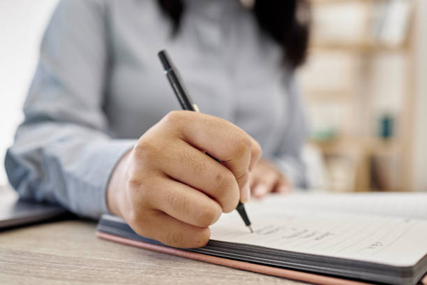 istock Planning, writing and hands of woman with notebook at desk in office for learning, notes and checklist. Brainstorming, strategy and closeup of female person with pen write ideas, schedule or reminder 1620402356