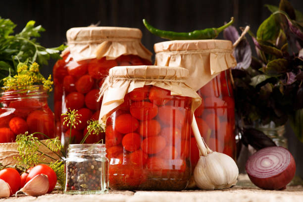 istock Pickled cherry tomatoes in jars and spices on a wooden background 1620409457