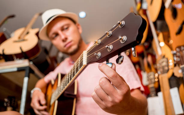 istock Young musician tuning a classical guitar in a guitar shop 1620420043