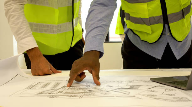 istock Hands of foreman use finger pointing on blueprint discussion with partner builder plan detail renovation at workplace. Engineer point on paper plan team building on sit. Teamwork contractor concept. 1620421066