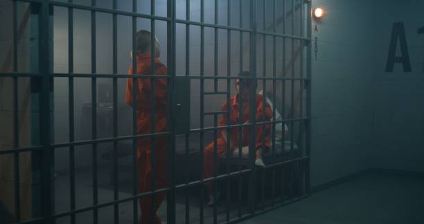 istock Two female prisoners in orange uniforms talk in prison cell 1620421079