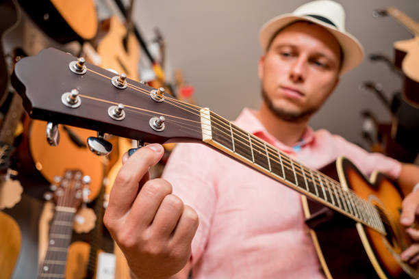istock Young musician tuning a classical guitar in a guitar shop 1620422948