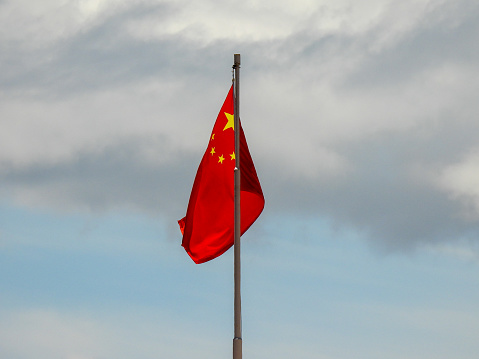 The flag of the People's Republic of China on an external wall around the People's Liberation Army Hong Kong Garrison Building in Admiralty.  This image was taken from Tamar Street on a hot, humid and sunny afternoon on 10 July 2023.