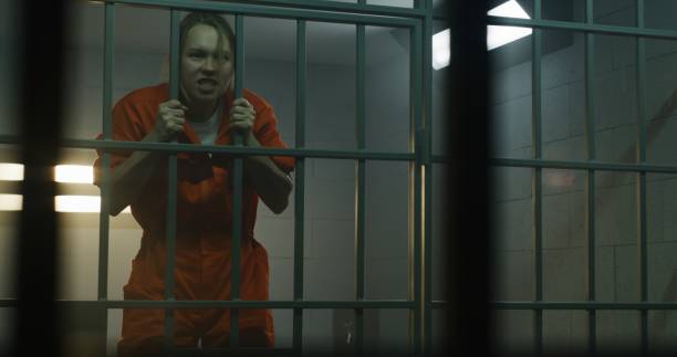 istock Insane female prisoner yells, jumps on bars in prison cell 1620454508