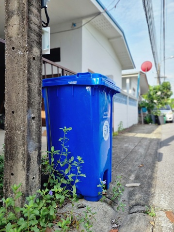 blue recycling bin with wheels made of plastic Place it outdoors on the sidewalk to collect garbage outside.