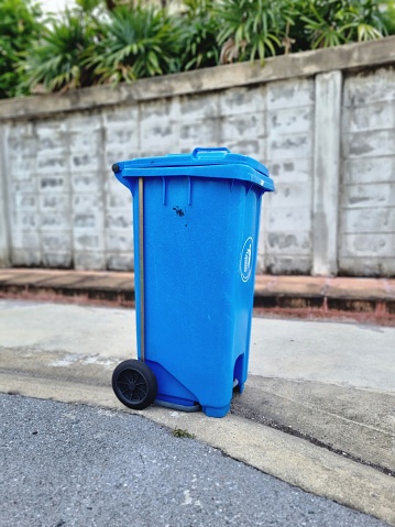 blue recycling bin with wheels made of plastic Place it outdoors on the sidewalk to collect garbage outside.