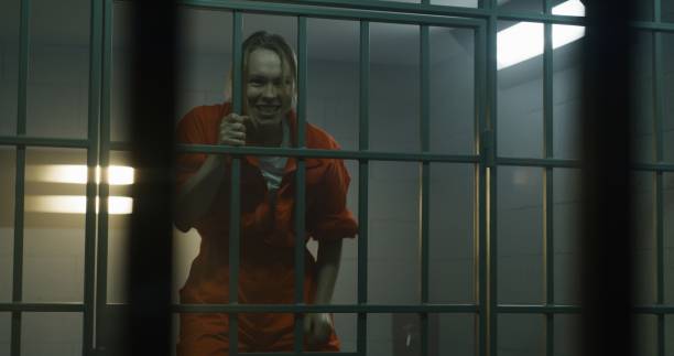 istock Insane female prisoner yells, jumps on bars in prison cell 1620457324