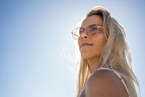 Portrait of a beautiful young woman wearing sunglasses standing outdoors on a sunny day