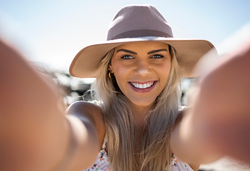 Attractive young woman taking selfie on beach vacation during summer