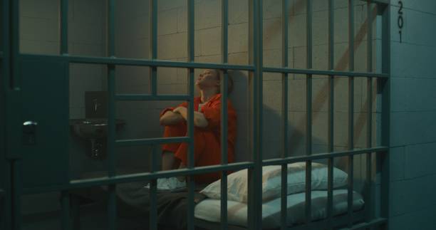istock Female prisoner sitting on the bed in jail cell 1620481053