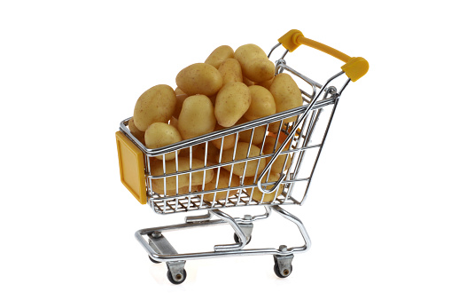 Supermarket trolley full of raw baby potatoes close up on white background