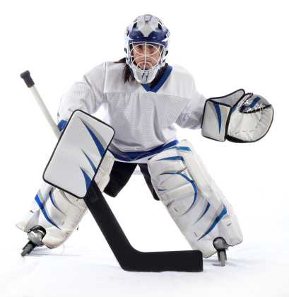 Frontal shot of a young hockey goaltender in a ready stance on a white background.