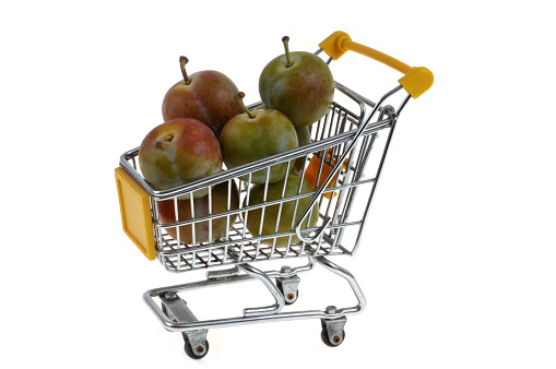 Supermarket trolley full of greengage close-up on white background