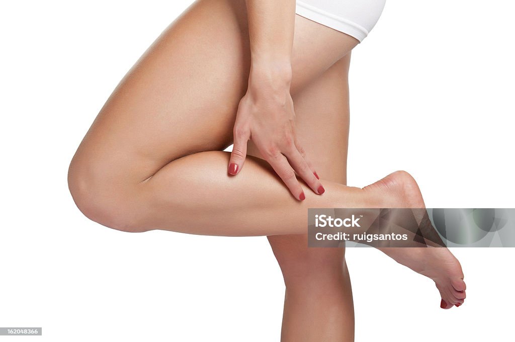 A woman touching her calf on her left leg Female with pain in her lower leg, isolated in white Adult Stock Photo