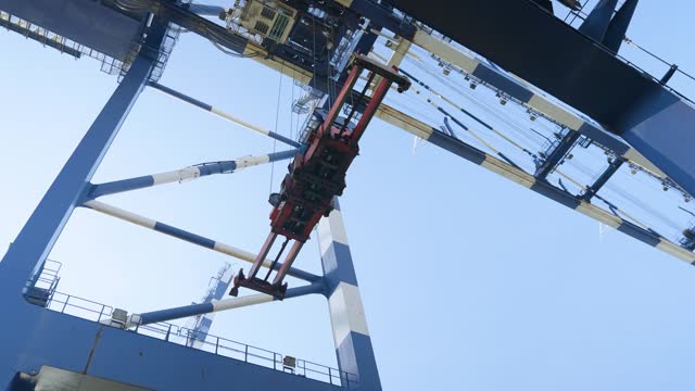 4K footage from underneath port crane stock video. Crane lifting and placing cargo container stock video.