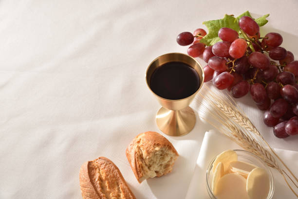 чаша на столе с хлебом и виноградом на заднем плане - communion table стоковые фото и изображения