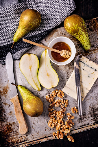 Overhead view of a flat lay arrangement of all the ingredients needed to make, baked pears with gorgonzola cheese, thyme, walnuts and a honey glaze. Colour, vertical format with some copy space.