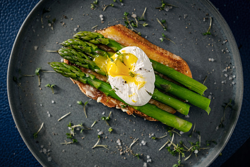 Eggs Benedict with asparagus on freshly toasted bread.  Colour, horizontal format with some copy space.