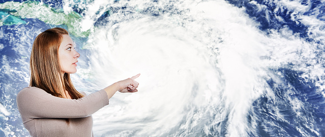 Young woman gestures towards image of a powerful hurricane. Weather image from www.nasa.gov/sites/default/files/thumbnails/image/matthew_tmo_2016278_lrg.jpg