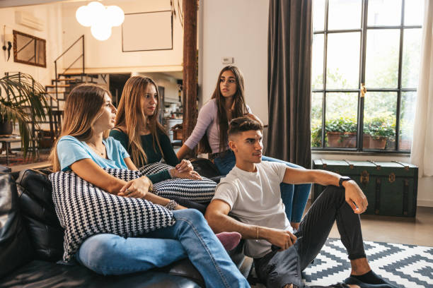 Four friends relaxing watching tv in the living room.