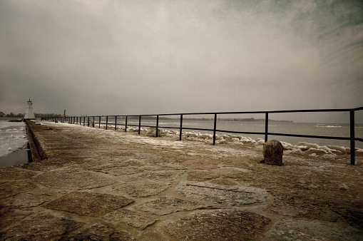 Softly textured image of pier with lighthouse in winter.