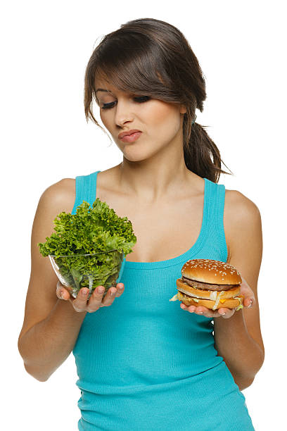 vacilan mujer que toma entre ensalada saludable y de comida rápida - hesitating fotografías e imágenes de stock