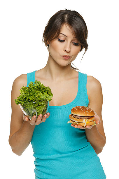 vacilan mujer que toma entre ensalada saludable y de comida rápida - hesitating fotografías e imágenes de stock