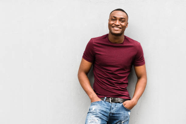 istock handsome young African American man leaning against gray wall and smiling 1620558199