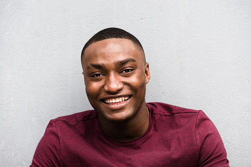 Close up portrait happy young African American man laughing against gray background