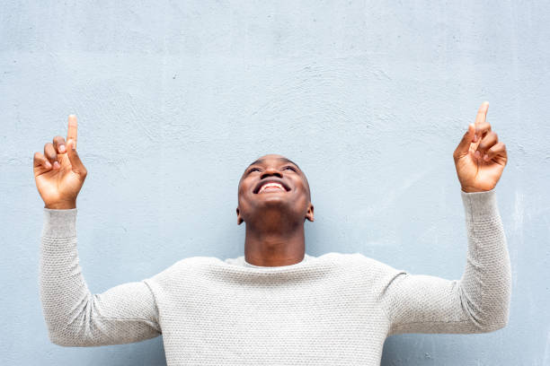 istock smiling African american man looking and pointing fingers up 1620559838