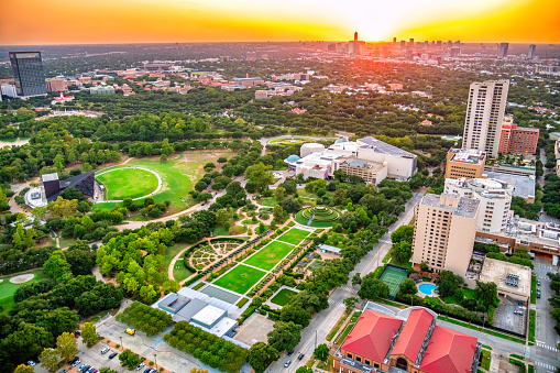 Aerial drone views with green Trees and summer landscape , bright colorful Colorado River and bridges connecting north and south Austin , Texas , USA The downtown Skyscrapers and partly cloudy skies , a beautiful sunny day in Central Texas