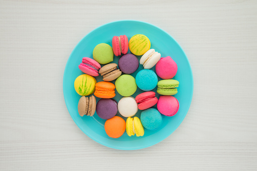 Colorful France macaroons on blue plate with white table background copy space. French food, culture, food design concept.