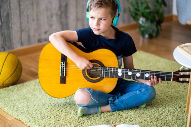 istock Boy playing acoustic guitar at home 1620587109