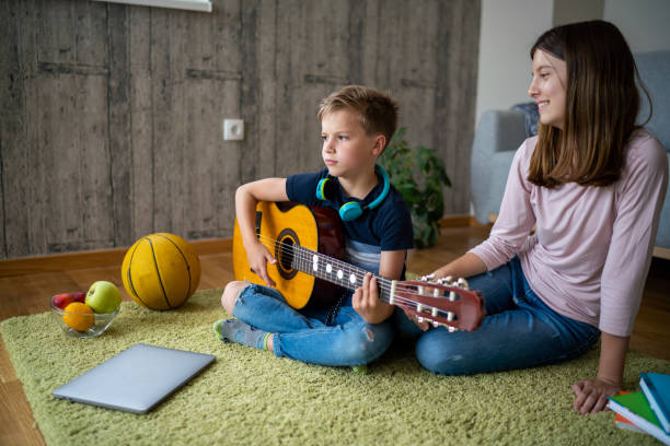 istock Boy playing guitar whit her sister at home 1620587655