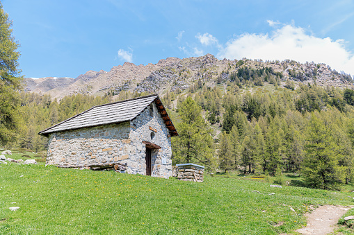 A scenics view of a mountain chapel (Chapelle des Séyères) and cross surrounded by grass and pine trees