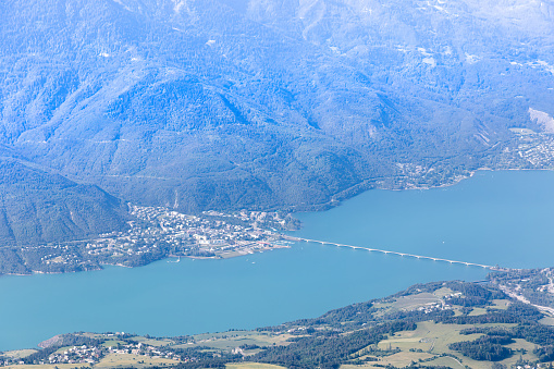 A scenics aerial view from the mountain of the of Savines-le-Lac, hautes-alpes, France town and valley with beautiful lake and bridge